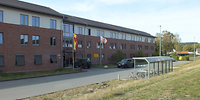 Blick auf einen dreigeschossigen Neubaublock mit teilweise rot verklinkerter Fassade