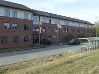 Blick auf einen dreigeschossigen Neubaublock mit teilweise rot verklinkerter Fassade