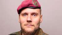 Ein Soldat mit weinrotem Barett schaut in die Kamera.