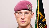 Ein Soldat mit weinrotem Barett schaut in die Kamera.