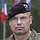 Ein deutscher Soldat steht vor mehreren Flaggen auf einem Paradeplatz.