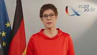 Annegret Kramp-Karrenbauer is standing in front of flag from the EU and Germany