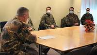 Soldaten sitzen um einen Tisch und tauschen sich untereinander aus