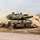 Ein Kampfpanzer Leopard fährt durch das Gelände und wirbelt Staub auf