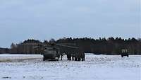 Eine Gruppe Soldaten steht am gelandeten Hubschrauber. Ein Verantwortlicher erklärt und zeigt etwas.