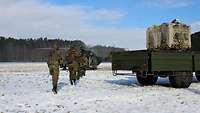 Ein Trupp Soldaten geht auf den gelandeten Hubschrauber zu und steigt ein, rechts steht ein Lkw.