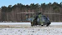 Die letzten Soldaten steigen in den Hubschrauber ein, der mit rotierenden Rotorblättern auf einem verschneiten Feld steht.