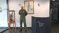 Der Kommodore des TLG 31 steht vor einem Portrait. Neben ihm steht der Prinz-Heinrich-Preis in einer Vitrine.