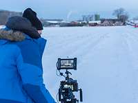 Der Kameramann macht in aller Frühe mitten in der Schneelandschaft Aufnahmen vom Bauernhof
