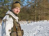 Der Oberfeldwebel, im Schneetarn, lächelt in die Kamera