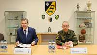 Der Kommandeur und der Parlamentarische Staatssekretär sitzen nebeneinander. 