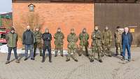 Die Soldaten des Leichten Spähzuges stehen gemeinsam mit dem Landwirt vor der Scheune.