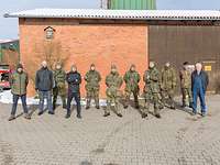 Die Soldaten des Leichten Spähzuges stehen gemeinsam mit dem Landwirt vor der Scheune.