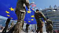 Soldaten verschiedener Nationen halten EU-Flagge