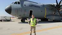 Eine Soldatin steht mit Warnweste vor dem grauen A400M