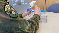 Ein Soldat klebt kleine Aufkleber auf Plastikröhrchen.