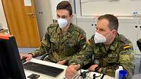 Zwei Soldaten sitzen vor einem Computer.
