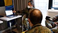 Mehrere Soldaten sitzen um ein Laptop herum