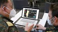 Zwei Soldaten sitzen vor einem Laptop