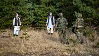 Zwei Soldaten stehen vor zwei, als Einheimische verkleide, Trainer.