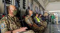 Mehrere Soldaten sitzen im A400M und folgen dem Gottesdienst. Der Militärpfarrer steht im Hintergrund vor einem Podest.