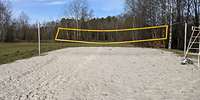 Mit hellem Sand aufgeschüttete Fläche, darüber ist ein Volleyballnetz gespannt.
