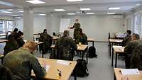 Soldaten sitzen in einem Containerhörsaal, der Ausbilder steht an einem Flipchart