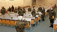 Soldaten stehen in einem großen Saal und grüßen den Kommandeur