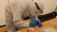 Ein Soldat in Vollschutz beschriftet eine soeben entnommene Probe