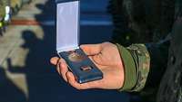 Ein Soldat hält eine Medaille in der Handfläche.