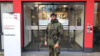 Der bärtige Soldat in Flecktarnuniform steht vor dem Eingang des Altenzentrums.