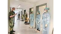 In einem Flur steht eine Gruppe von Menschen in Schutzkleidung. Sie bekommen eine Einweisung