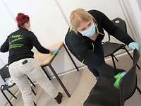 Zwei Frauen reinigen Tische und Stühle