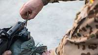 Ein Soldat hat einen Schrauber in der Hand und justiert ein Modul am Handgriff des Gewehr G36.