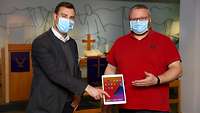 Militärpfarrer Tim Mahle (links) und Pfarrhelfer Holger Knieling zeigen das angeschaffte Tablet
