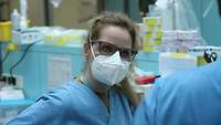 Portrait einer Frau in blauer Krankenhauskleidung, die ihren Gesprächspartner ansieht.