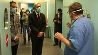 Verteidigungsminister Portugals informiert sich aus erster Hand Ein Mann in einem Anzug steht in einem Gang und lässt sich von einem Arzt in Krankenhauskleidung etwas erklären