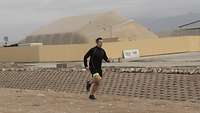 Ein Soldat joggt in einem zivilen Sportanzug. Im Hintergrund steht ein beigefarbenes großes Zelt.