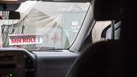 Blick durch die Frontscheibe eines Autos auf ein Schild mit der Aufschrift „MN Role 1“, dahinter ein Militärzelt 
