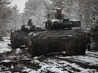 Zwei Schützenpanzer Puma fahren auf einem leicht verschneiten Waldweg hinter einander.