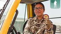 Eine Soldatin sitzt in einem Gabelstapler und hält stolz einen Patch ihres Einsatzverbandes in die Kamera