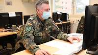 Ein Soldat sitzt in einem Unterrichtsraum an einem Bildschirmarbeitsplatz