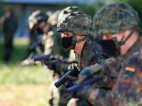Soldaten stehen mit Mund-Nasen-Schutz in einer Reihe und üben an einer Pistole.