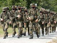 Mehrere Soldaten marschieren in Uniform nebeneinander.