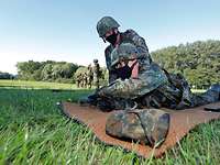 Zwei Soldaten üben mit einer Pistole auf einer Wiese.