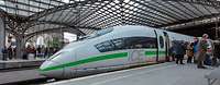 ICE in neuem Design mit grünem Streifen am Kölner Hauptbahnhof unter der Glaskuppel, im Hintergrund der Kölner Dom.