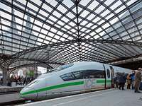 ICE in neuem Design mit grünem Streifen am Kölner Hauptbahnhof unter der Glaskuppel, im Hintergrund der Kölner Dom.