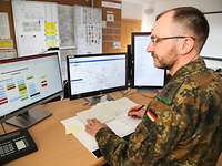 Soldaten in einem Raum mit Computern und Plänen.
