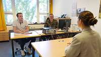 Frau sitzt vor zwei Männern zum Bewerbungsgespräch