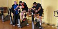Ein Ausbilder erklärt den Bewerbenden den Ergometertest